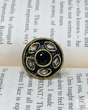 Black Kundan ring with white teardrop stones and antique gold finish on a black enamel base.