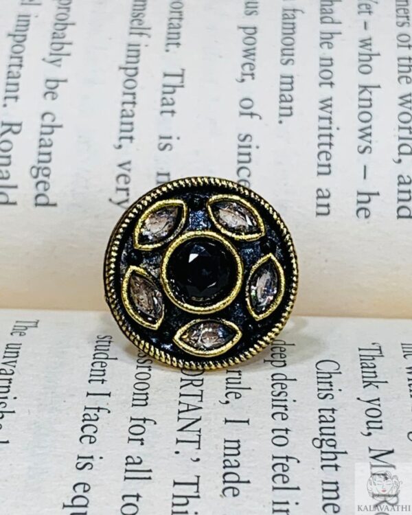 Black Kundan ring with white teardrop stones and antique gold finish on a black enamel base.