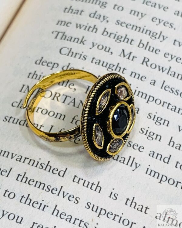 Statement ring featuring a deep black center stone with white accents and golden floral detailing.