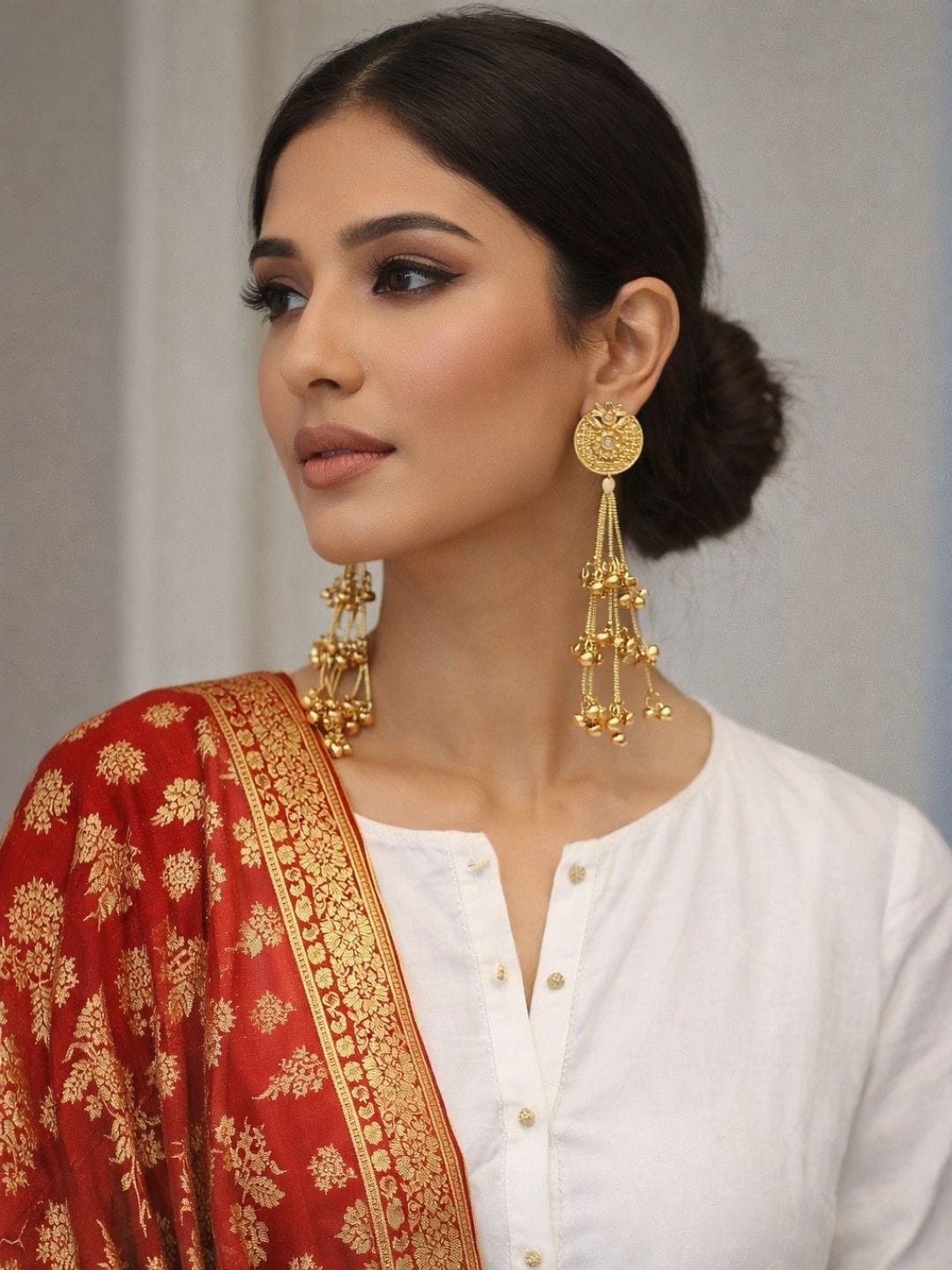 Gold finish ghungroo chain drop earrings with textured round studs worn with traditional outfit