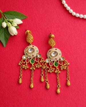Kundan gold finish chain drop earrings with multicolour stones and enamel detailing on festive background