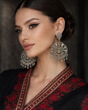 Peacock motif oxidised silver statement earrings with teardrop stones and pearl danglers on red background