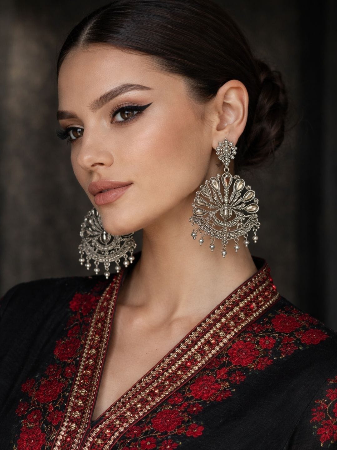 Peacock motif oxidised silver statement earrings with teardrop stones and pearl danglers on red background
