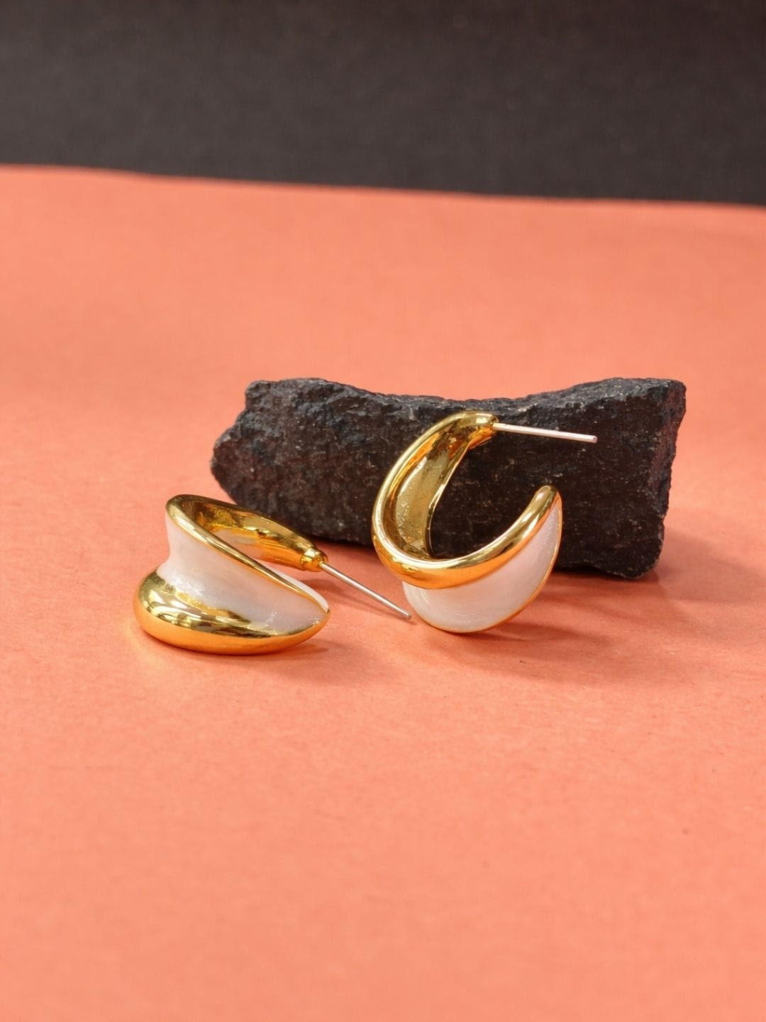 Gold finish half hoop stud earrings with white shell inlay on peach background