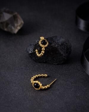 Gold beaded hoop stud earrings with black stone detailing on dark background