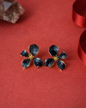 Black enamel floral gold stud earrings with anti-tarnish finish on red background