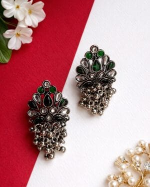 Handcrafted oxidised silver jhumka earrings with emerald green stones and ghungroo detailing styled on a model