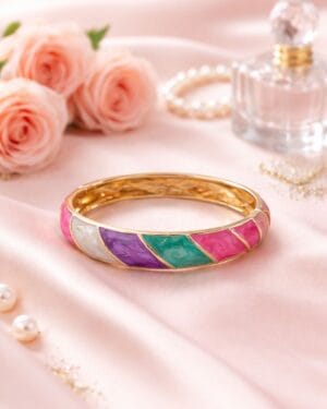 Gold-toned multicolour resin finish statement bangle on soft pink fabric background