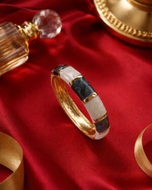 Gold toned black white resin openable bracelet on marble tray